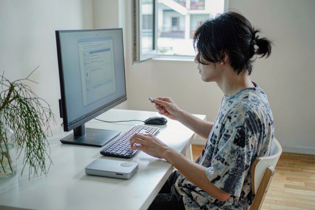 A person installing software on a desktop PC from a USB drive in a bright home office